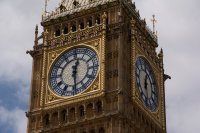 Zoomed in view of the face of Big Ben in London England showing the time as half past 12PM. The sky behind the tower is overcast.